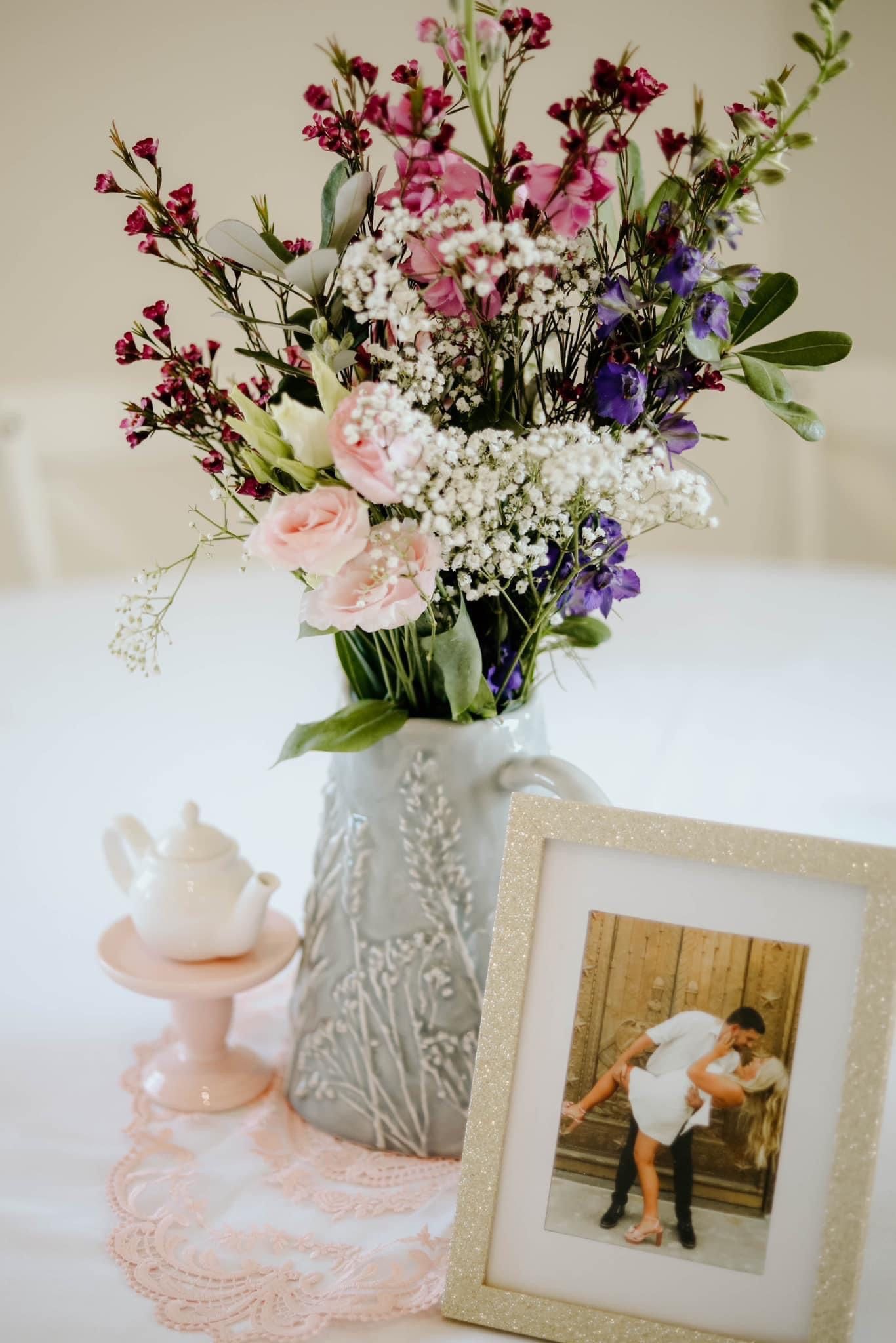 A vase filled with flowers and a picture of a couple on a table.