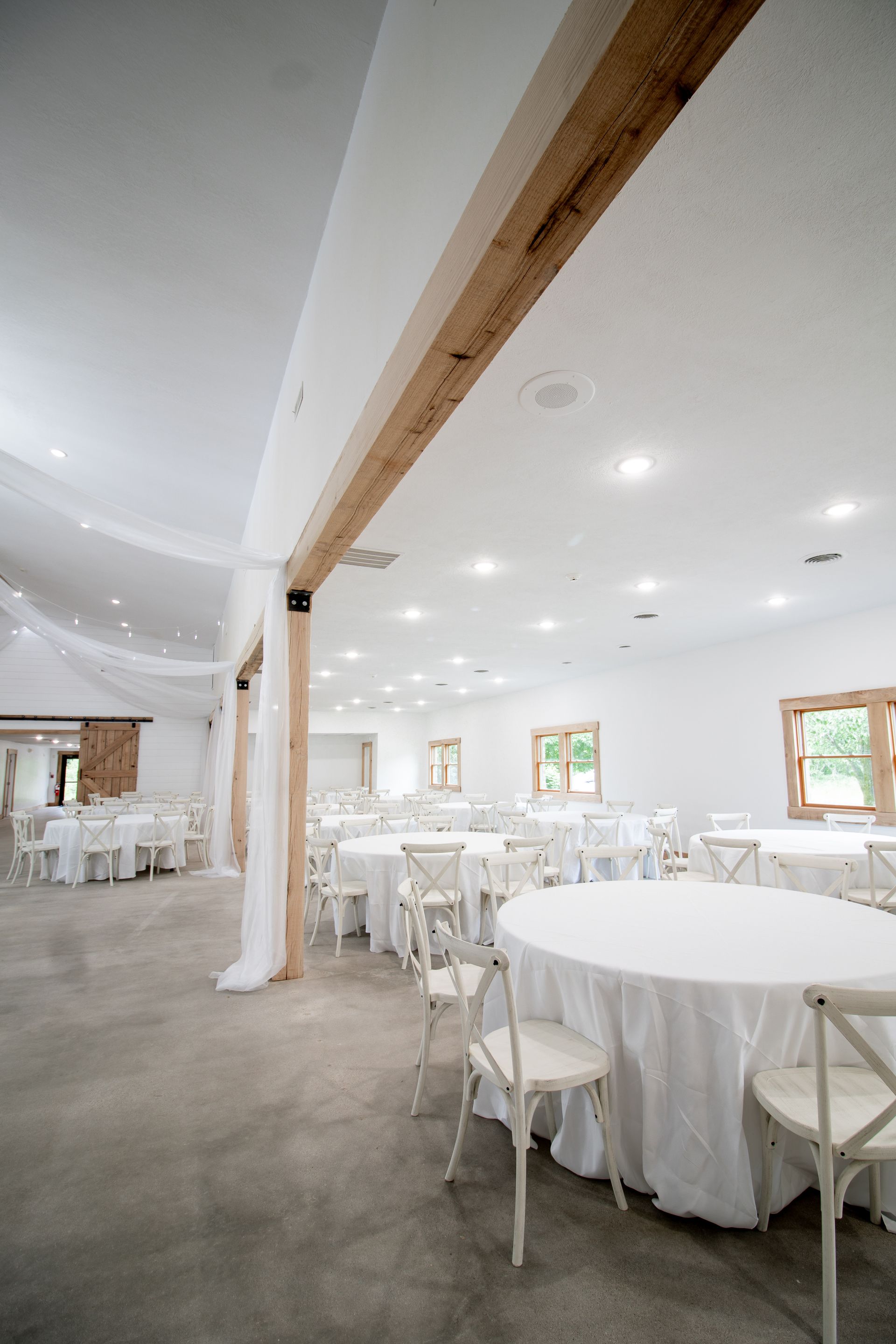 A large room with tables and chairs set up for a wedding reception.