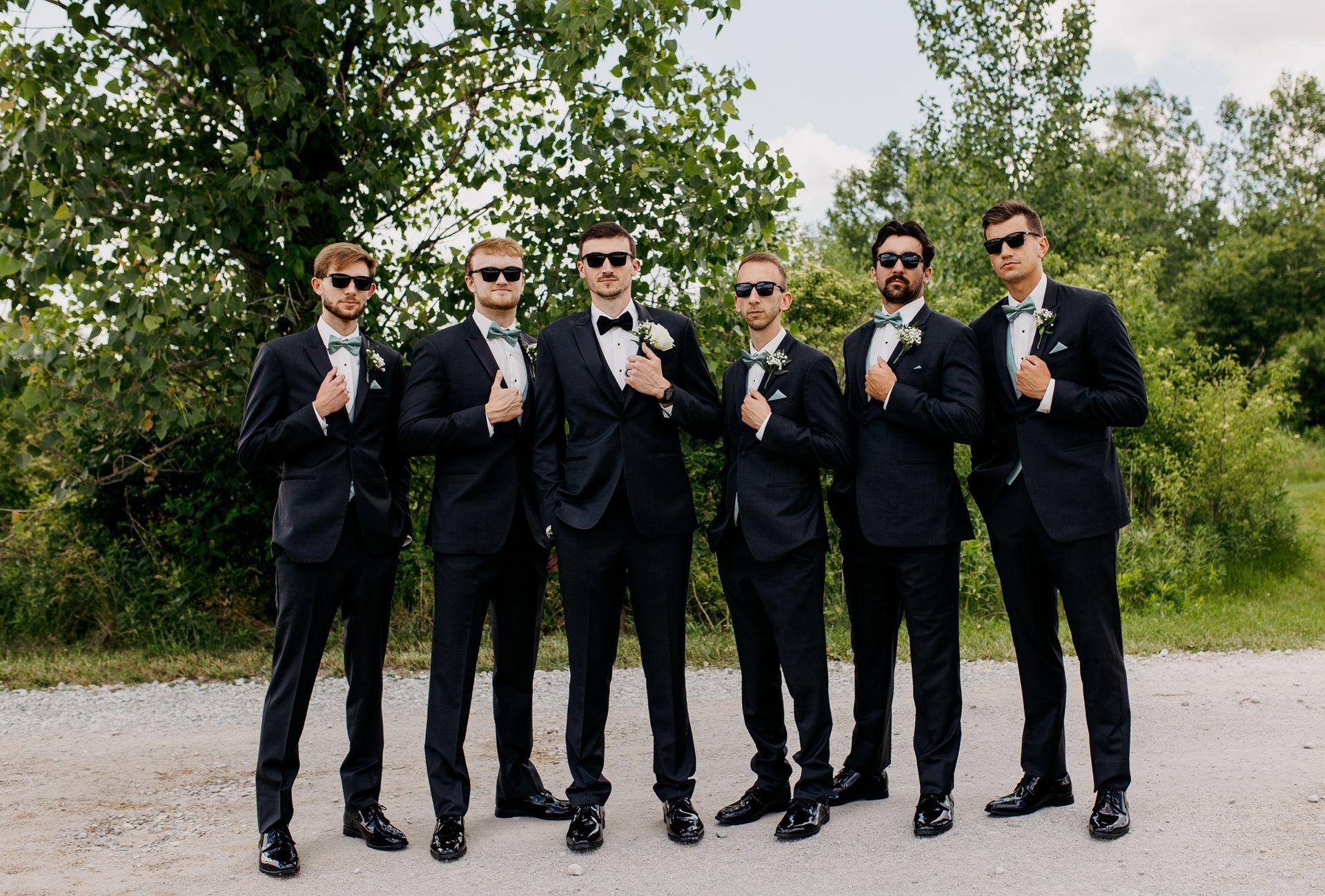 A group of men in suits and bow ties are posing for a picture.