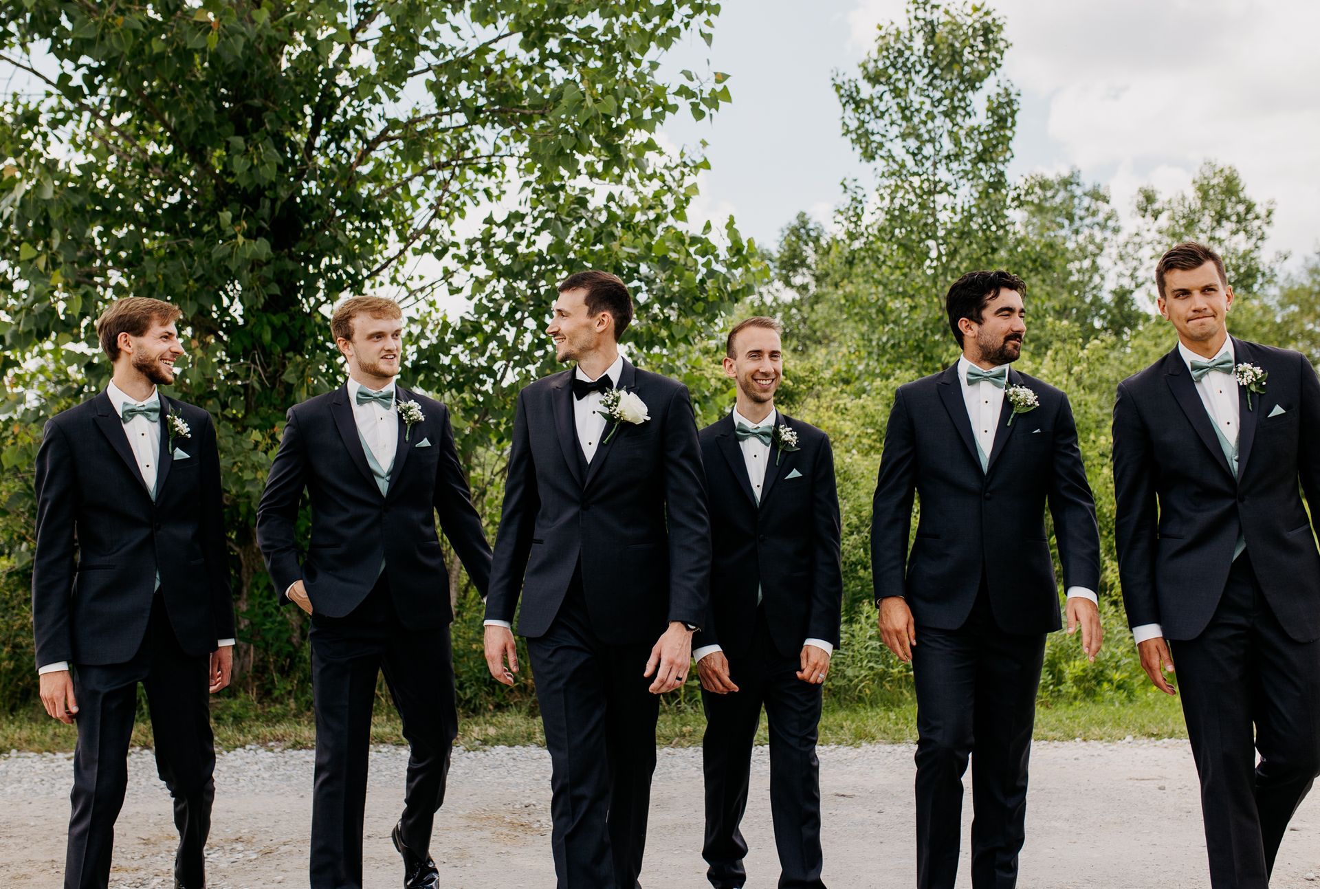 A groom and his groomsmen are walking down a road.