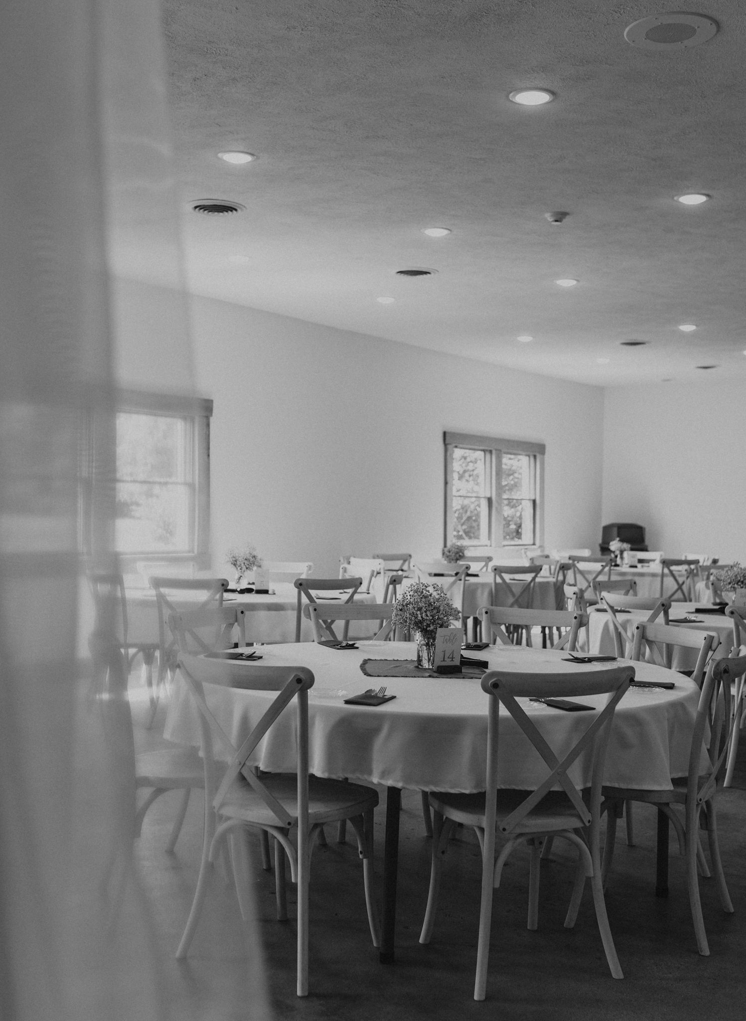 A black and white photo of a dining room filled with tables and chairs.
