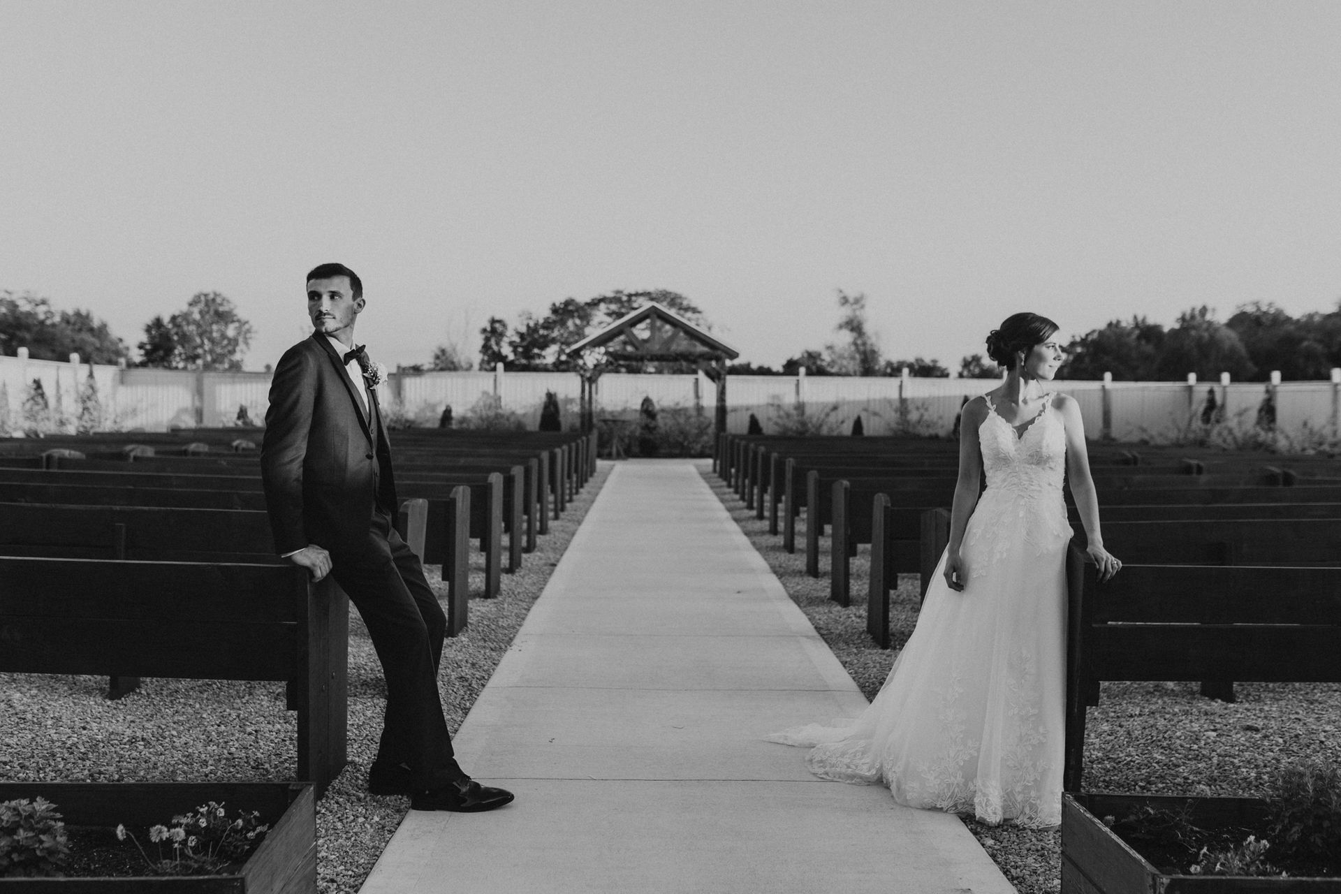 A bride and groom are standing next to each other on a concrete walkway.
