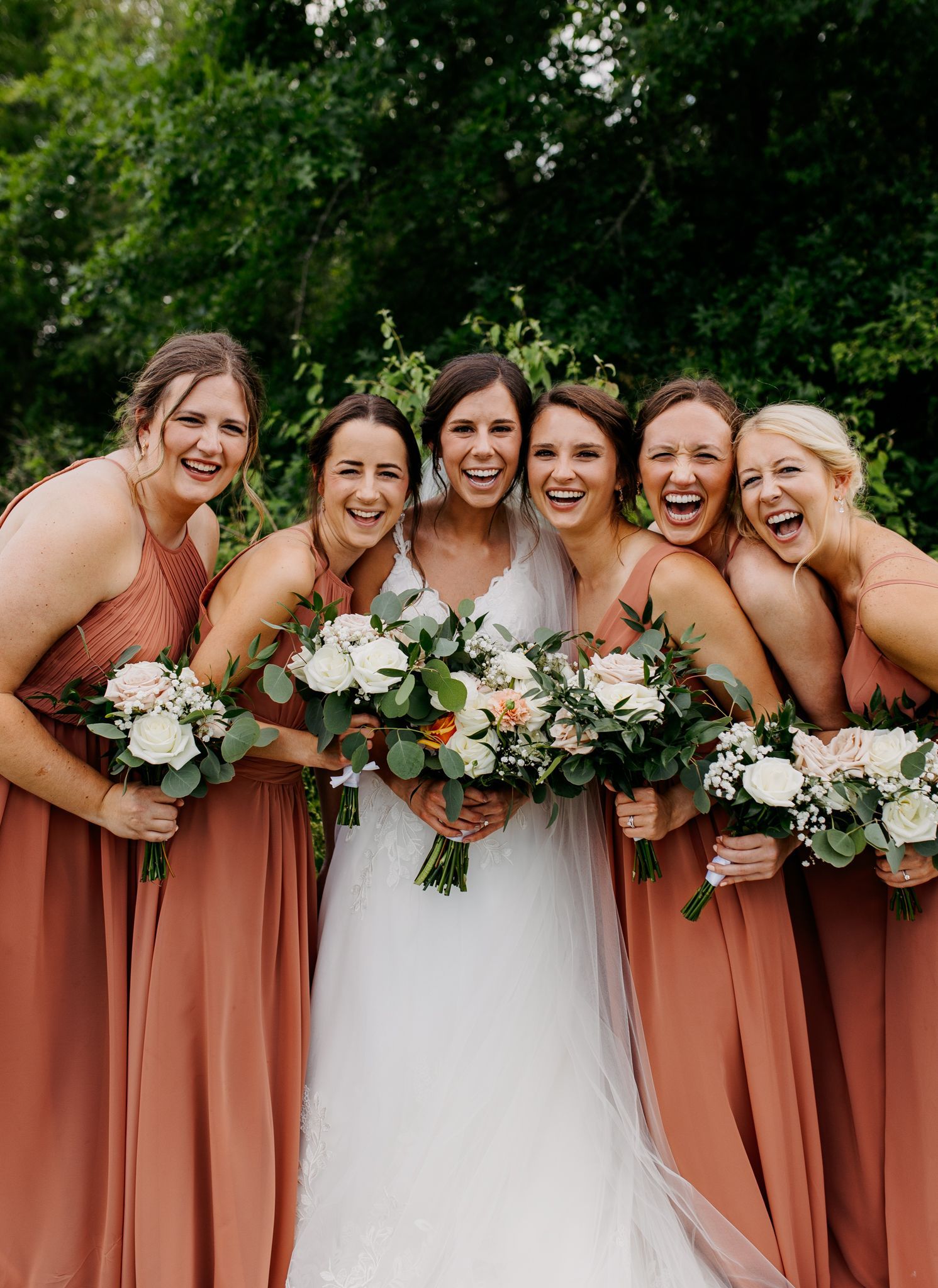 A bride and her bridesmaids are posing for a picture together.