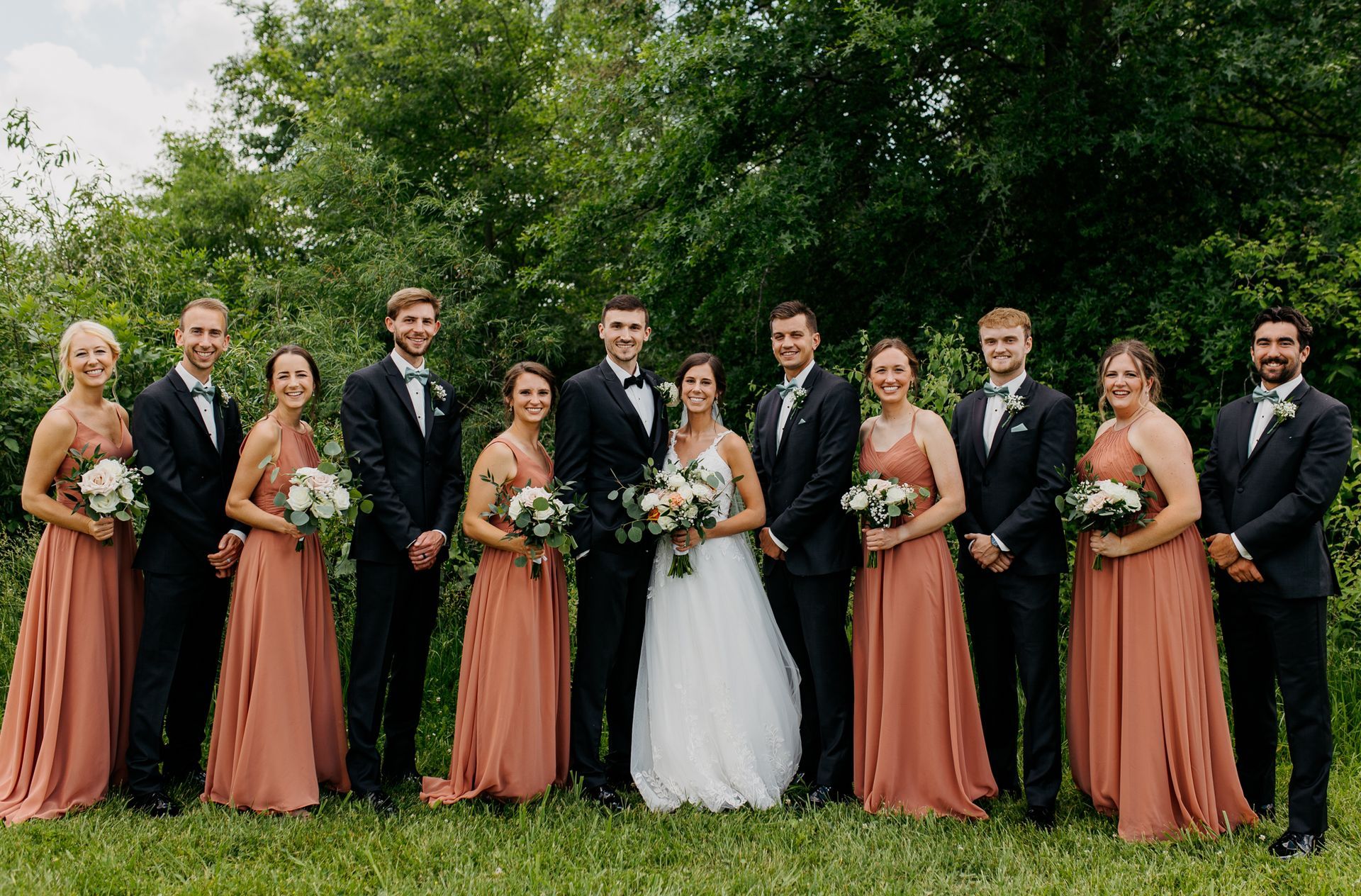 A bride and groom are posing for a picture with their wedding party.