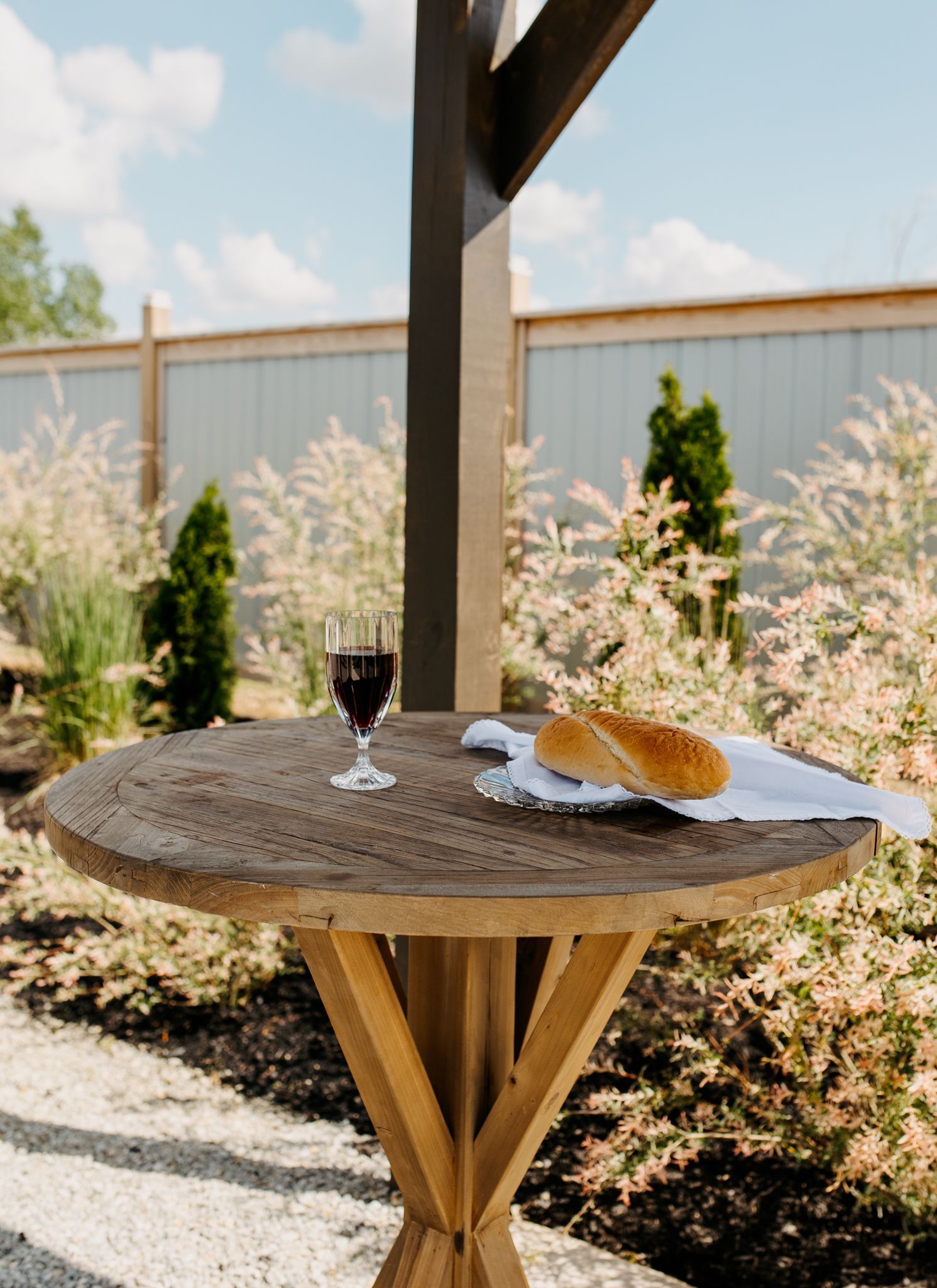 A wooden table with a loaf of bread and a glass of wine on it.