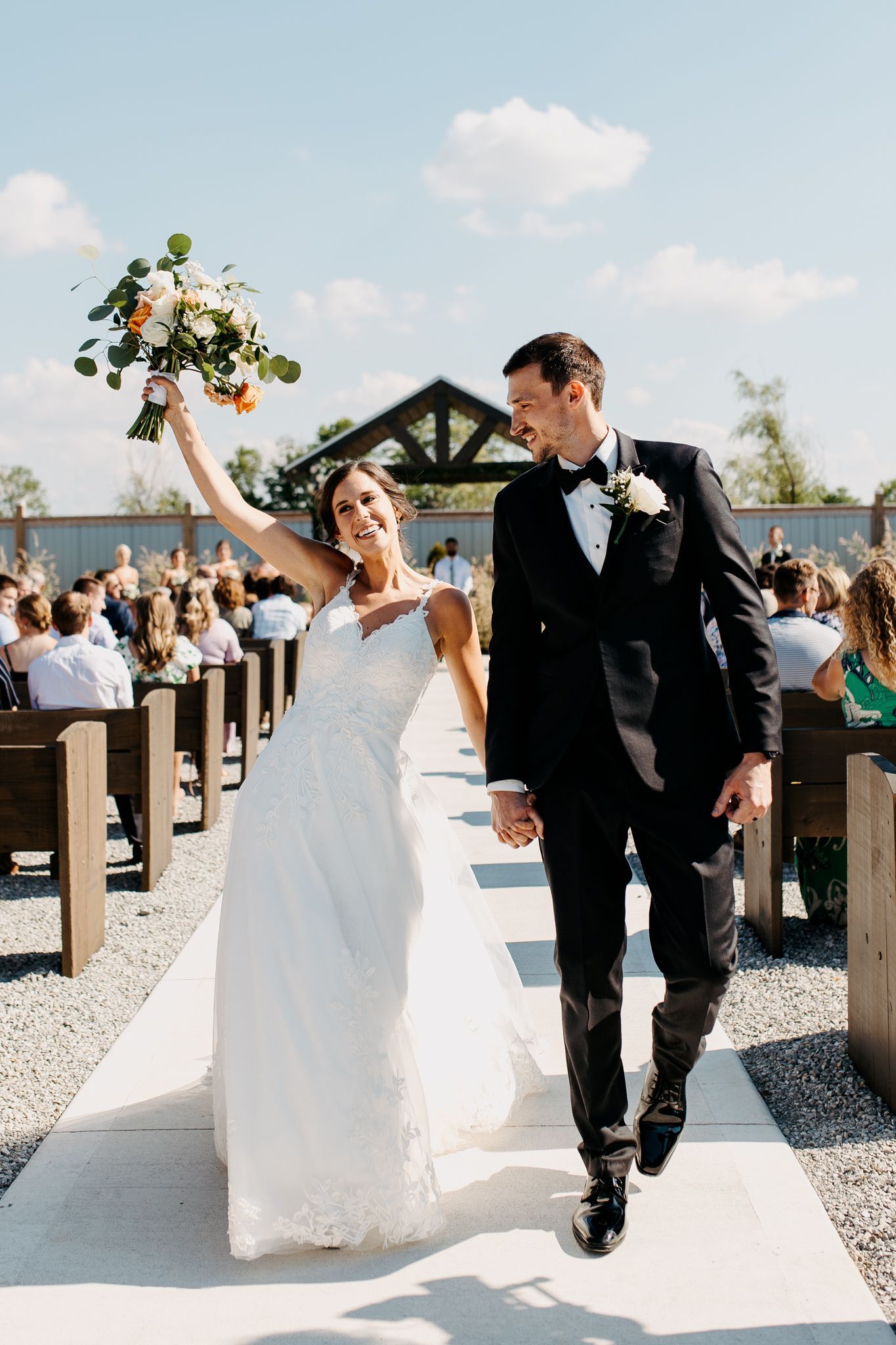 A bride and groom are walking down the aisle at their wedding holding hands.