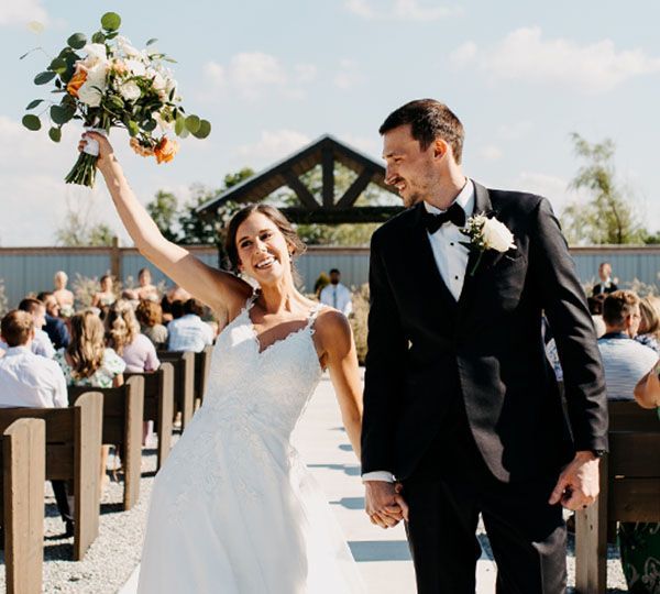 A bride and groom are walking down the aisle at their wedding