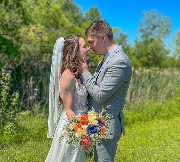 A bride and groom are kissing in a field on their wedding day.