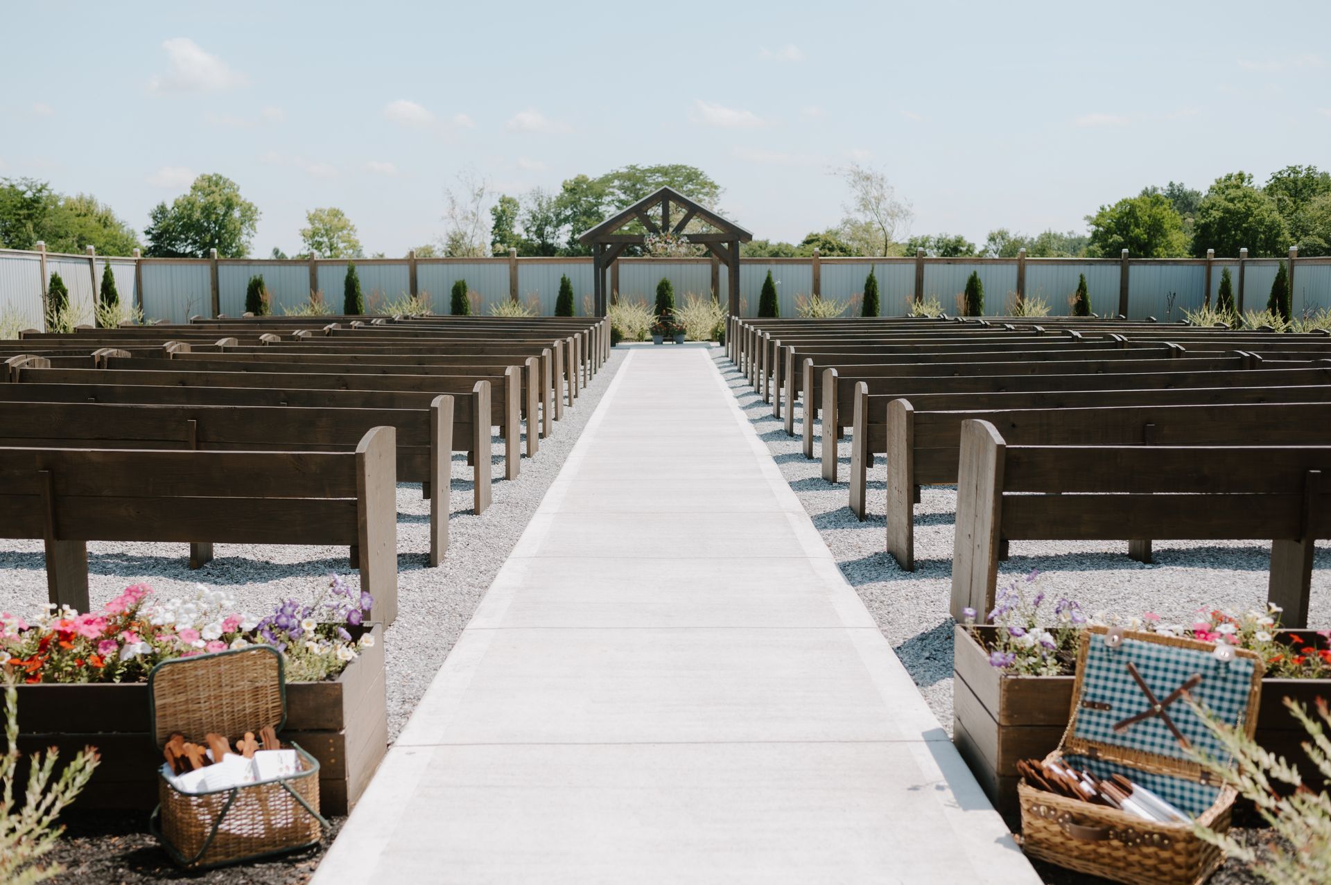 A long concrete walkway leading to a church with wooden benches.