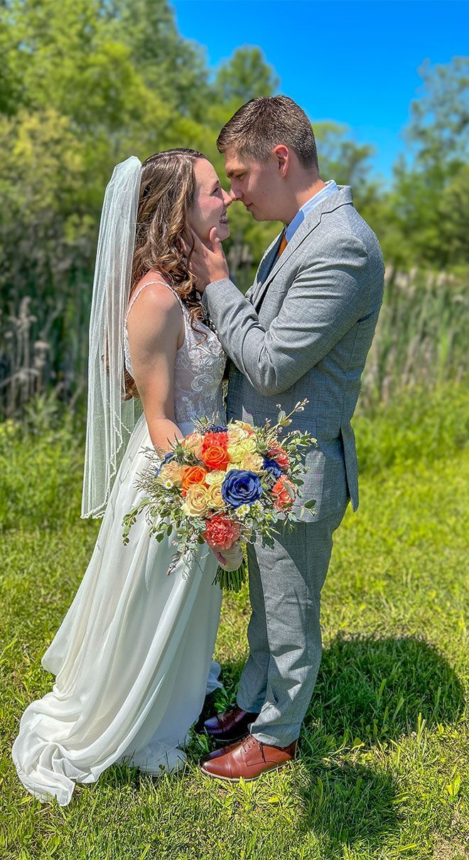 A bride and groom are kissing in a field on their wedding day.