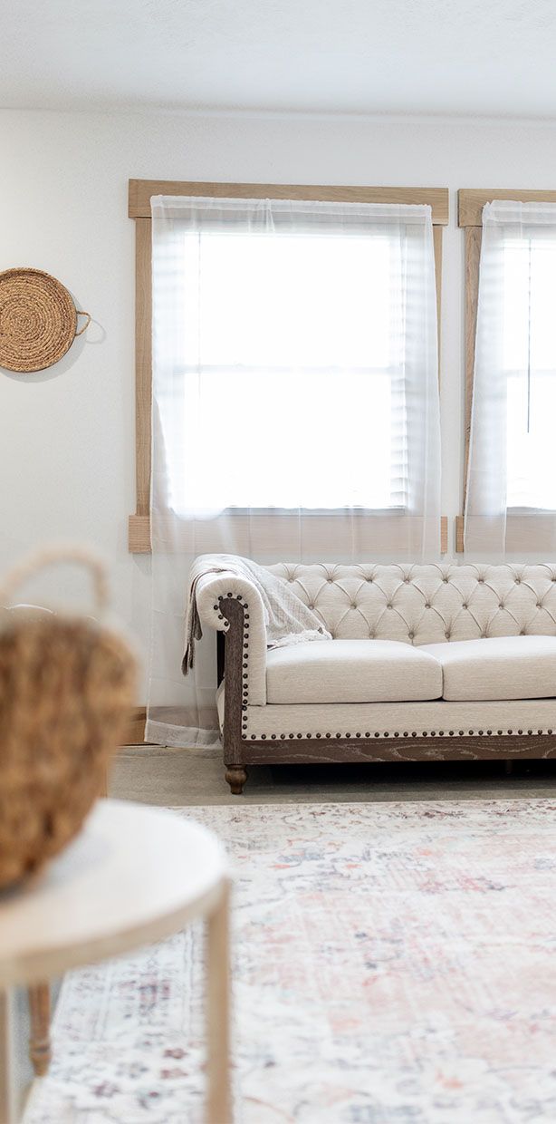 A living room with a white couch and two windows.