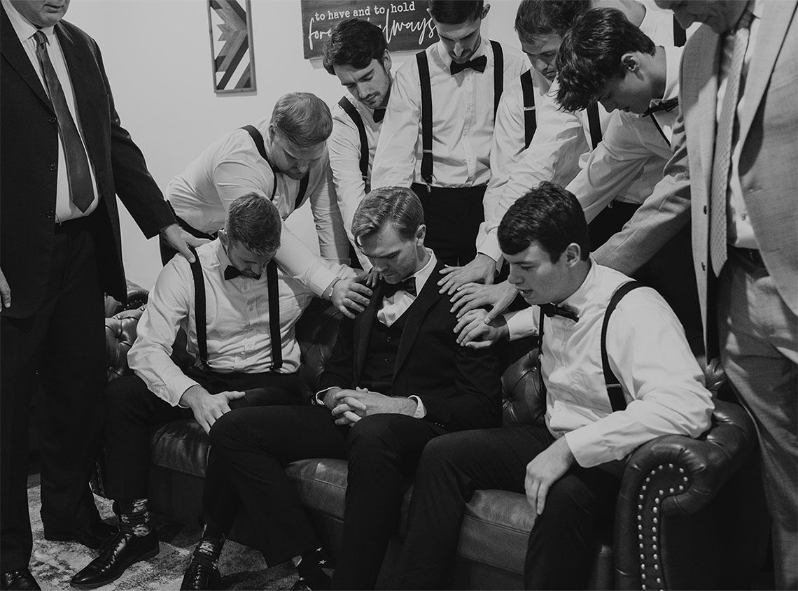 A group of men in suits and bow ties are sitting on a couch.