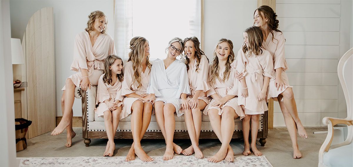 A bride and her bridesmaids are sitting on a couch.