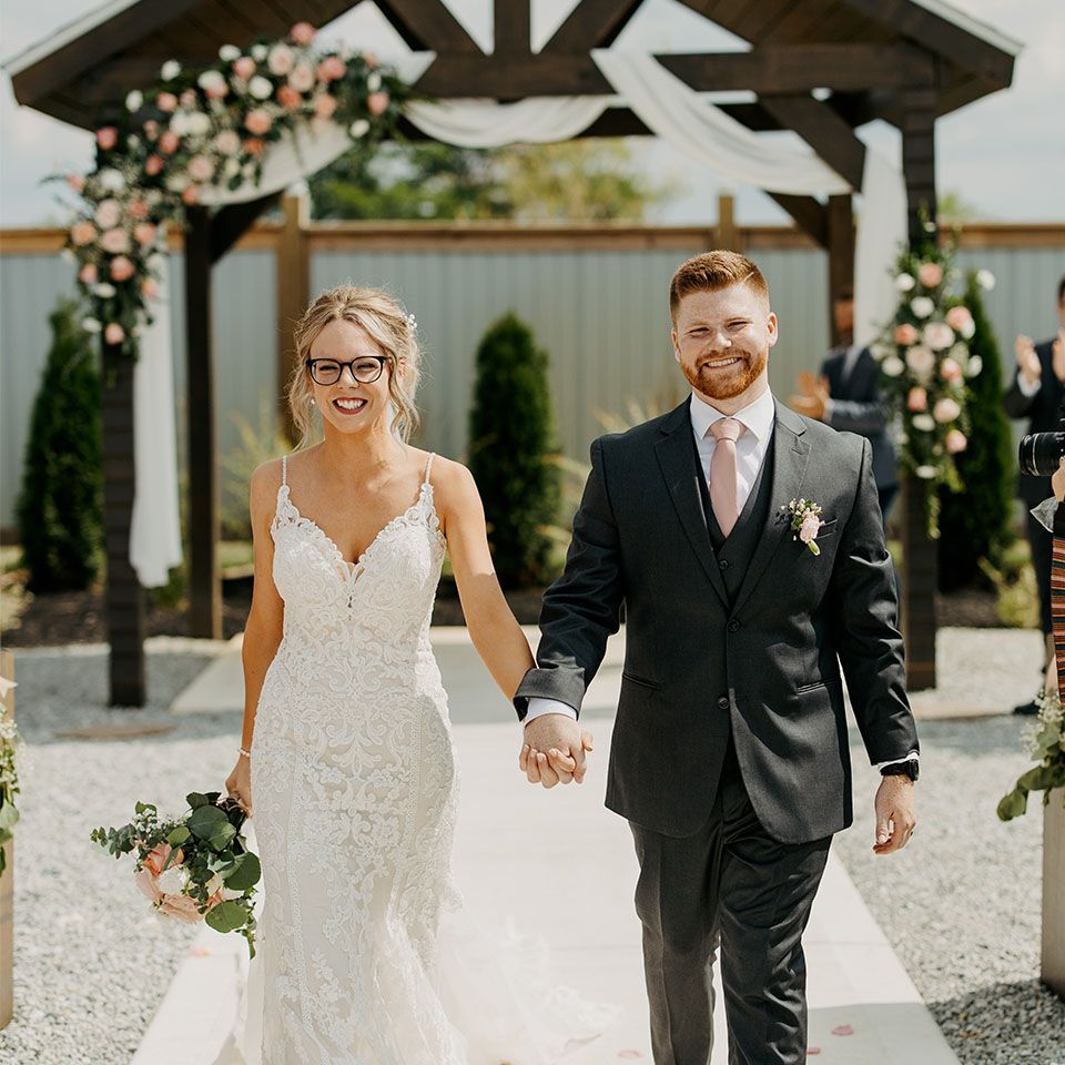 A bride and groom are walking down the aisle holding hands