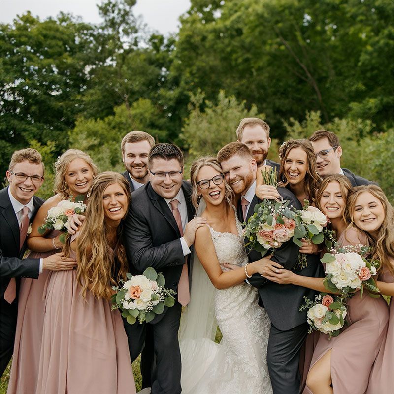 A bride and groom are posing for a picture with their wedding party.