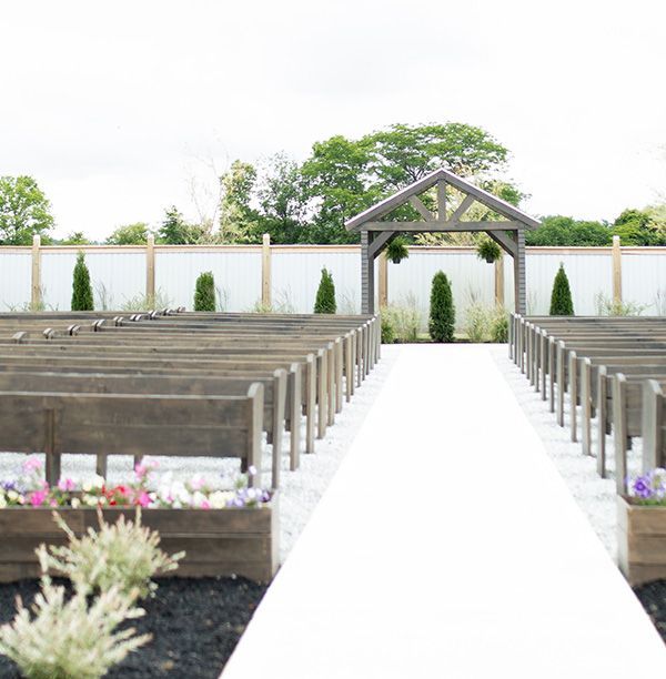 A row of wooden benches are lined up in a garden