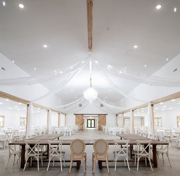 A large room with tables and chairs and a chandelier hanging from the ceiling.