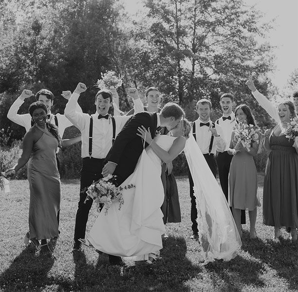 A bride and groom kissing in front of their wedding party