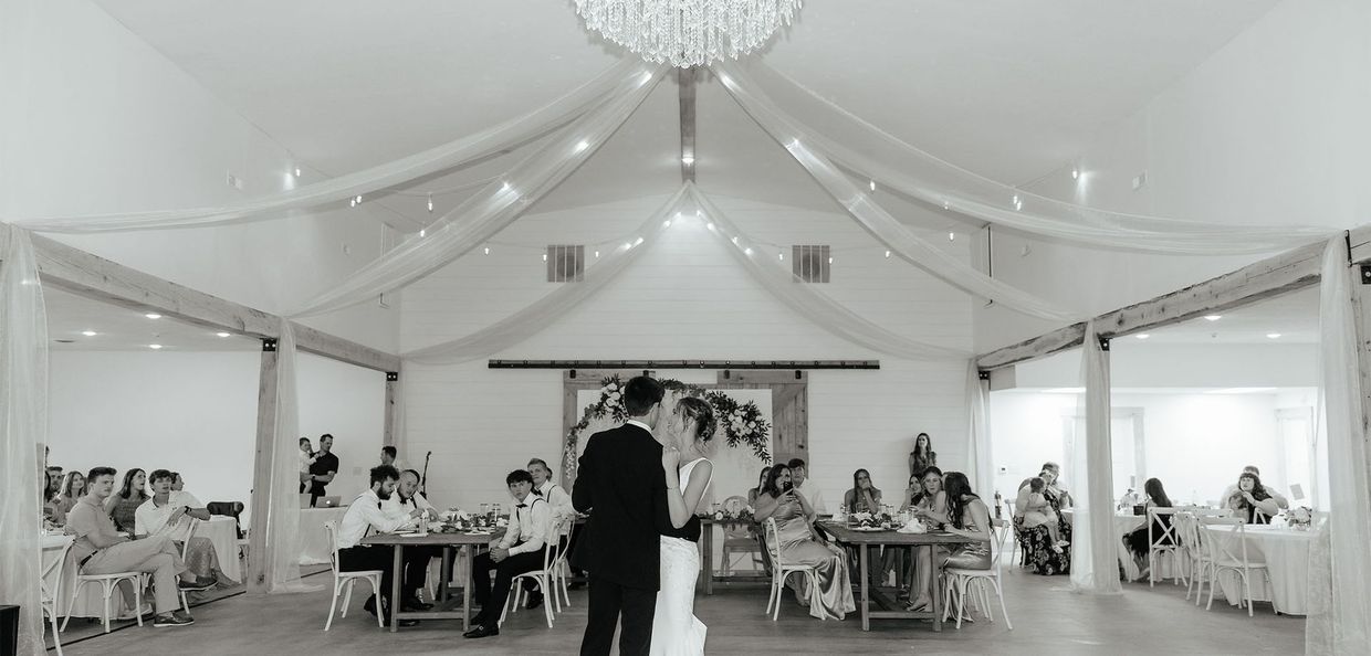 A black and white photo of a bride and groom dancing at their wedding reception.