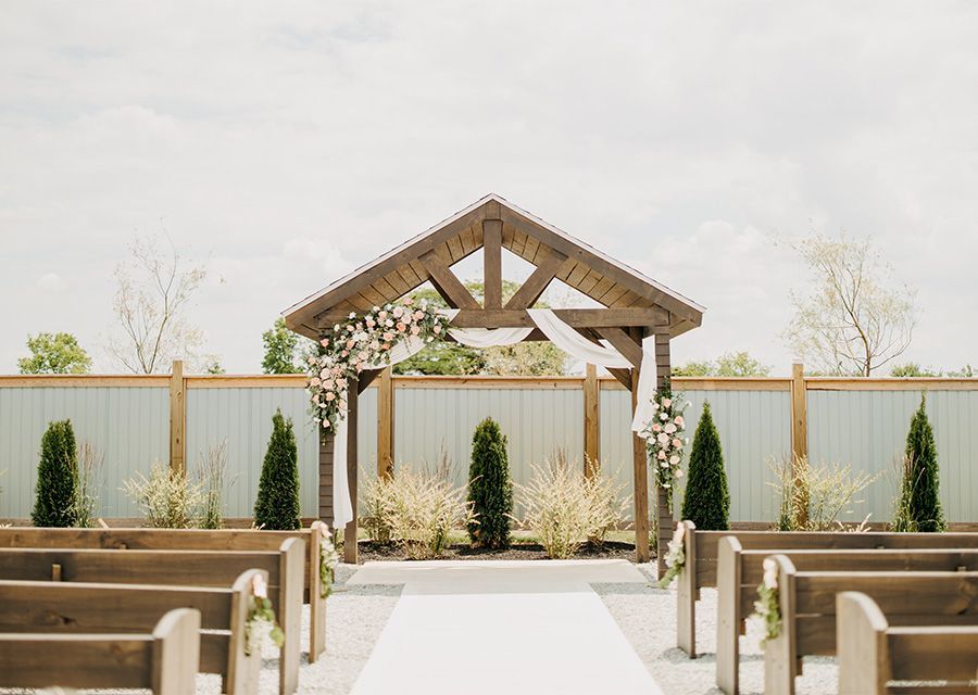 A wedding ceremony is taking place under a wooden archway.