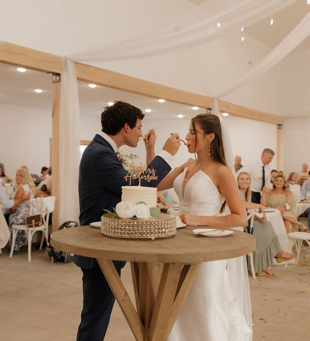 A bride and groom are feeding each other cake at their wedding reception