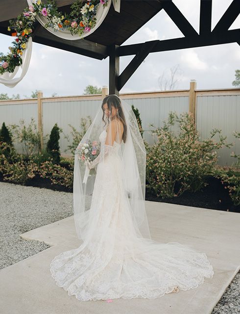 The bride is wearing a long veil and holding a bouquet of flowers