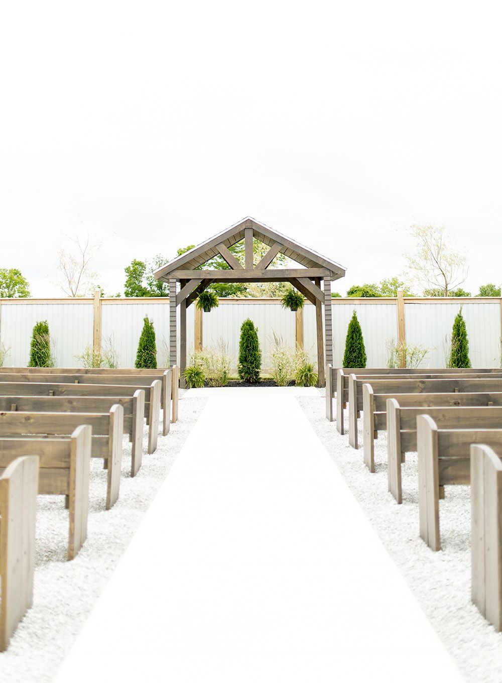 A row of wooden benches lined up in front of a wooden gazebo.