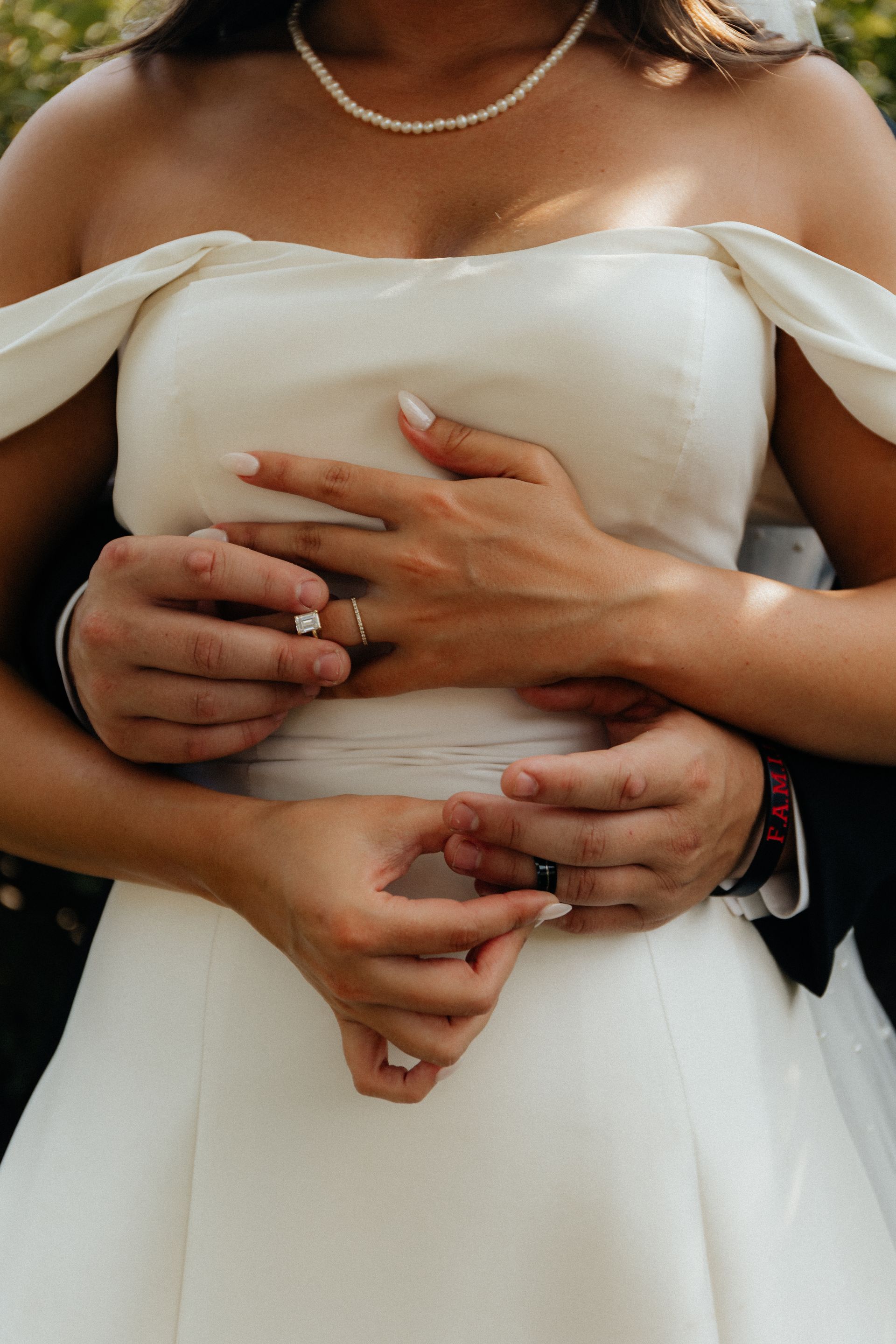 A bride and groom are hugging each other and the bride is wearing a wedding ring.