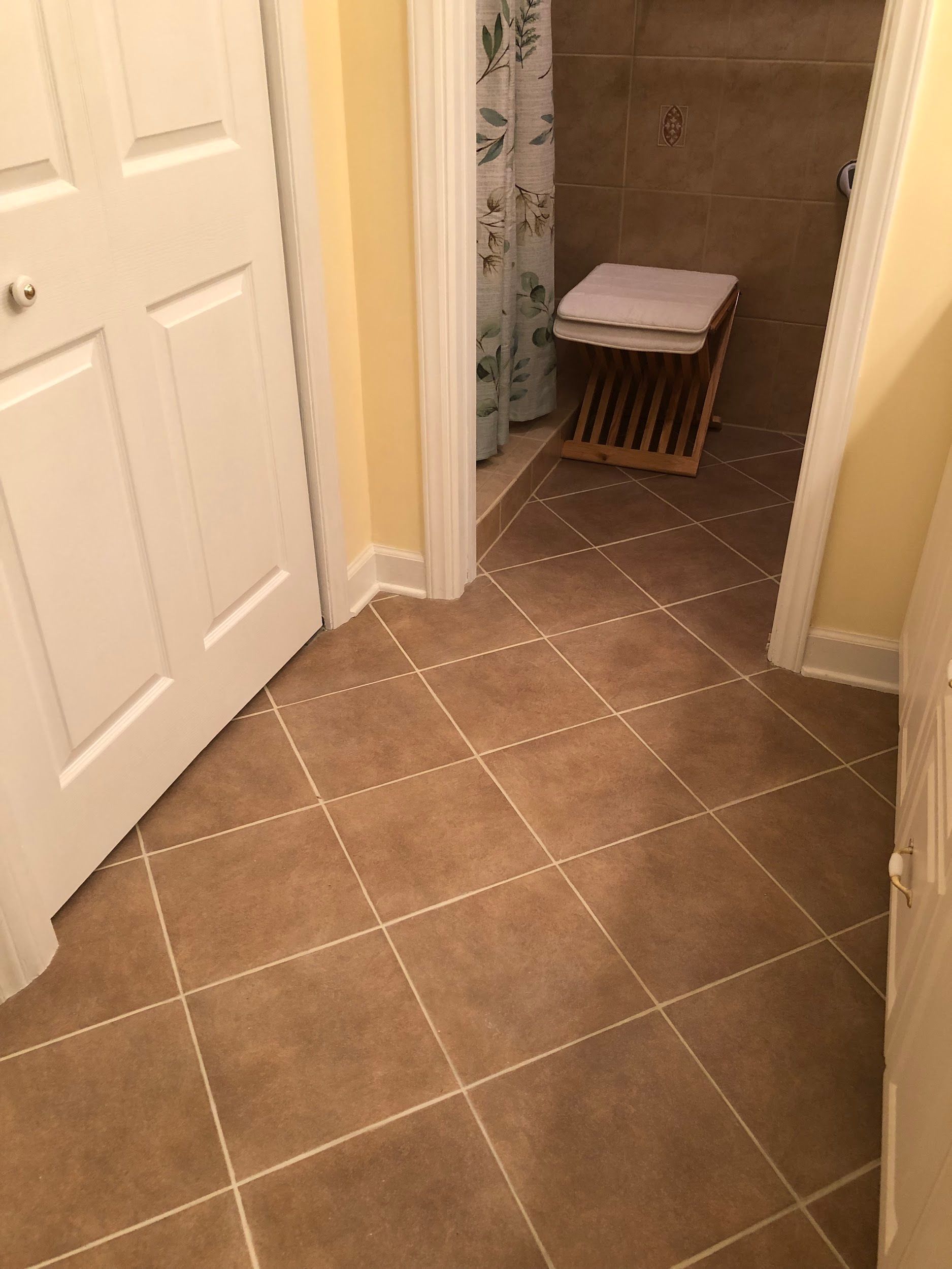 A bathroom with brown tile floors and a white door