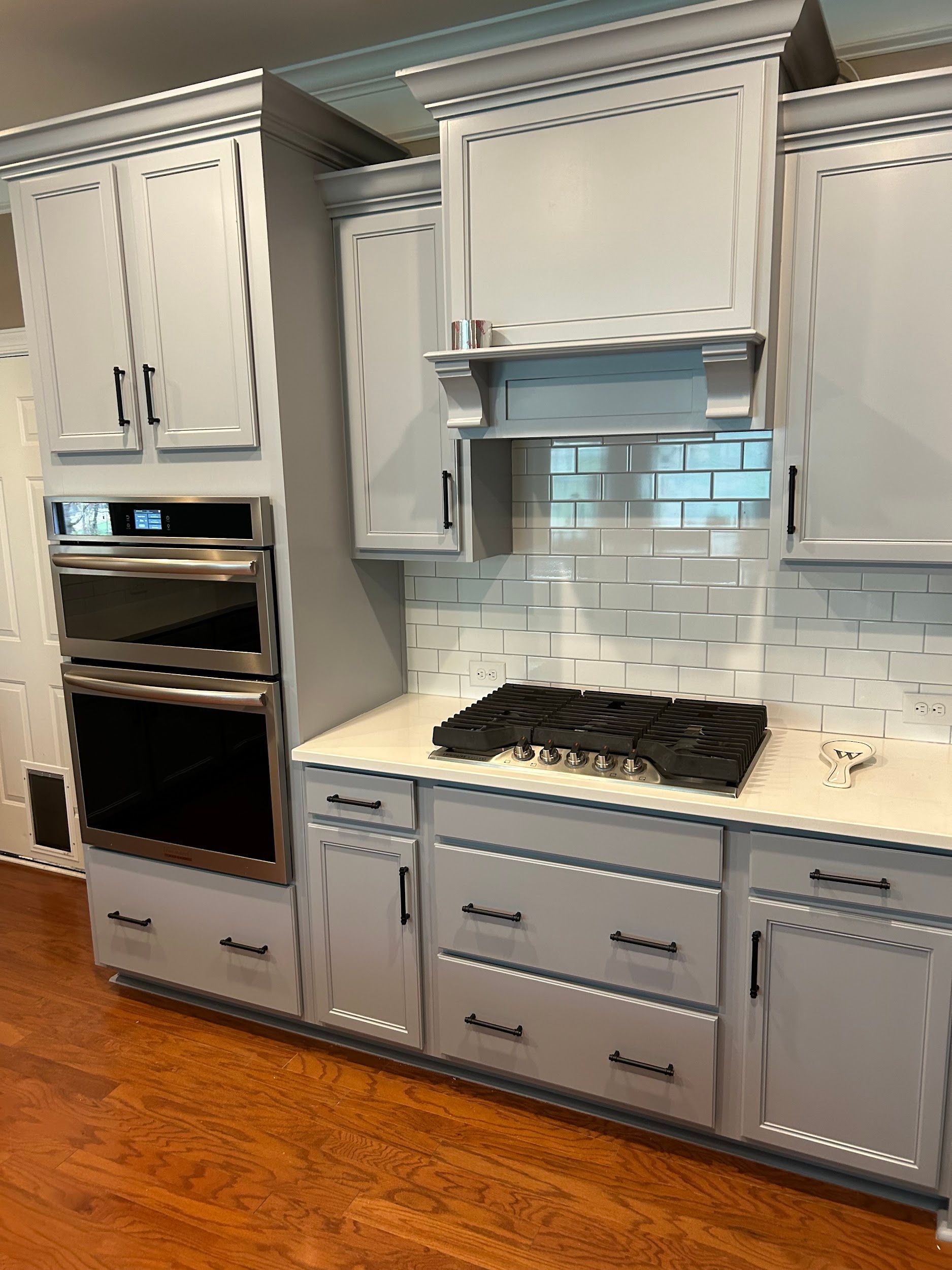 A kitchen with white cabinets and a stove top oven.