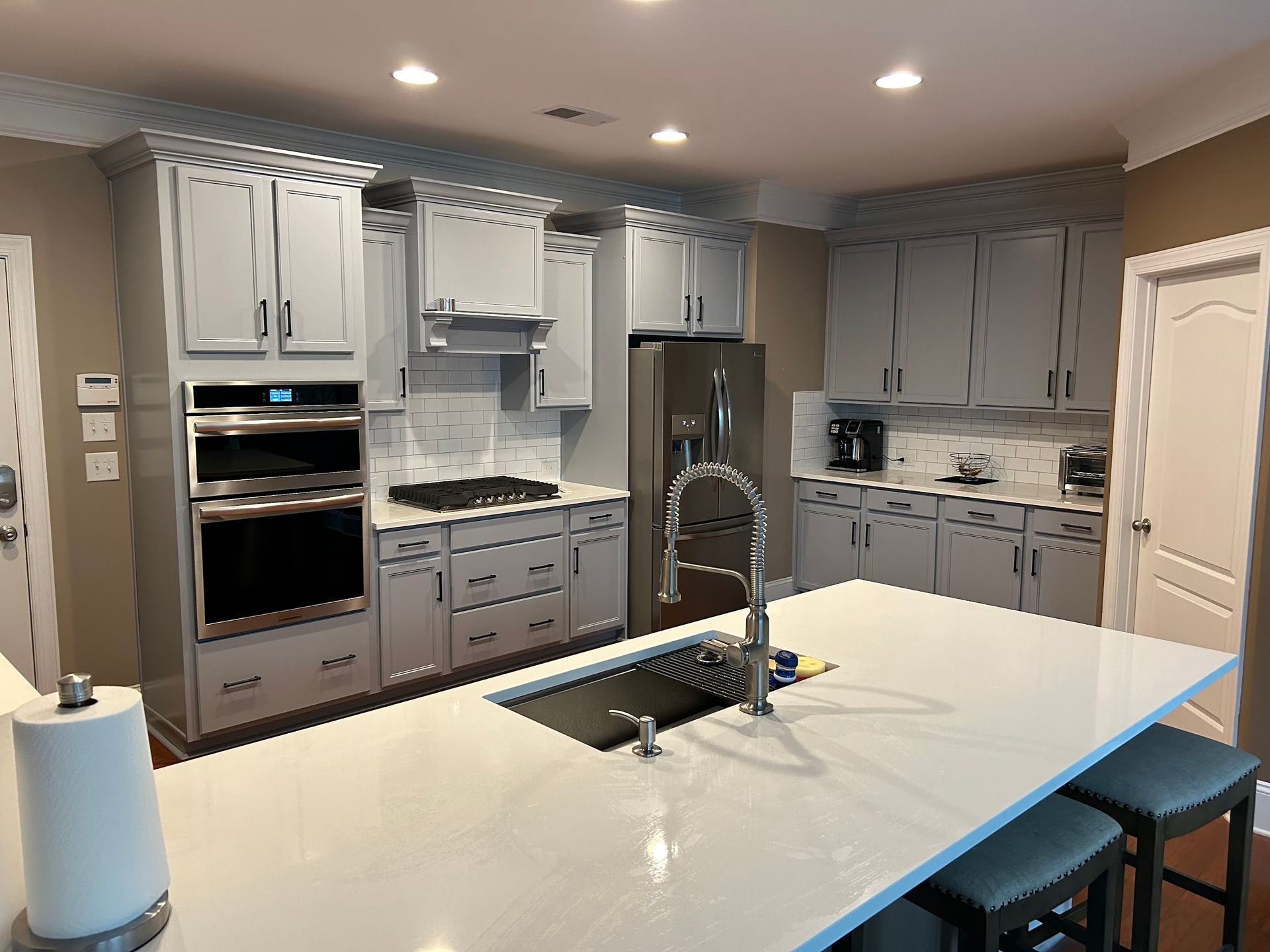 A kitchen with white cabinets , stainless steel appliances , a sink , and a large island.