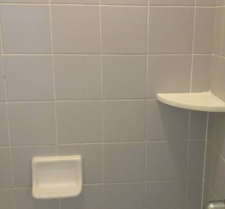 A bathroom with a soap dish and a shelf on the wall.