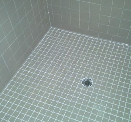 A tiled shower floor with a drain in the middle