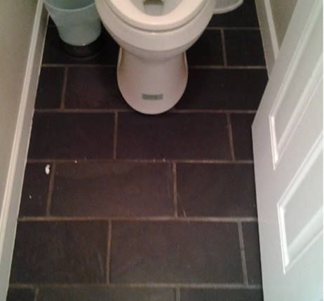 A toilet sits on a tiled floor in a bathroom