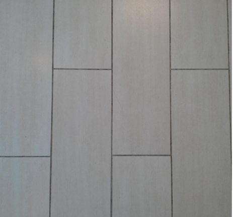 A close up of a white tile floor with a wood grain texture