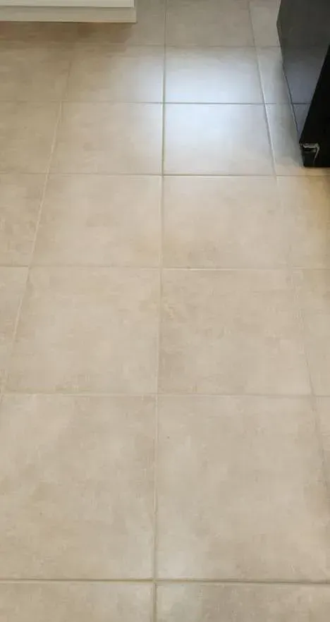A drain in a bathroom next to a tiled wall.