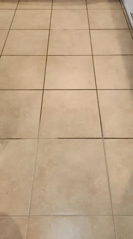A drain in a bathroom next to a tiled floor