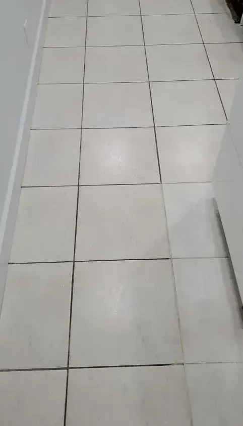 A close up of a corner of a tiled floor with a few pieces of wood on it.