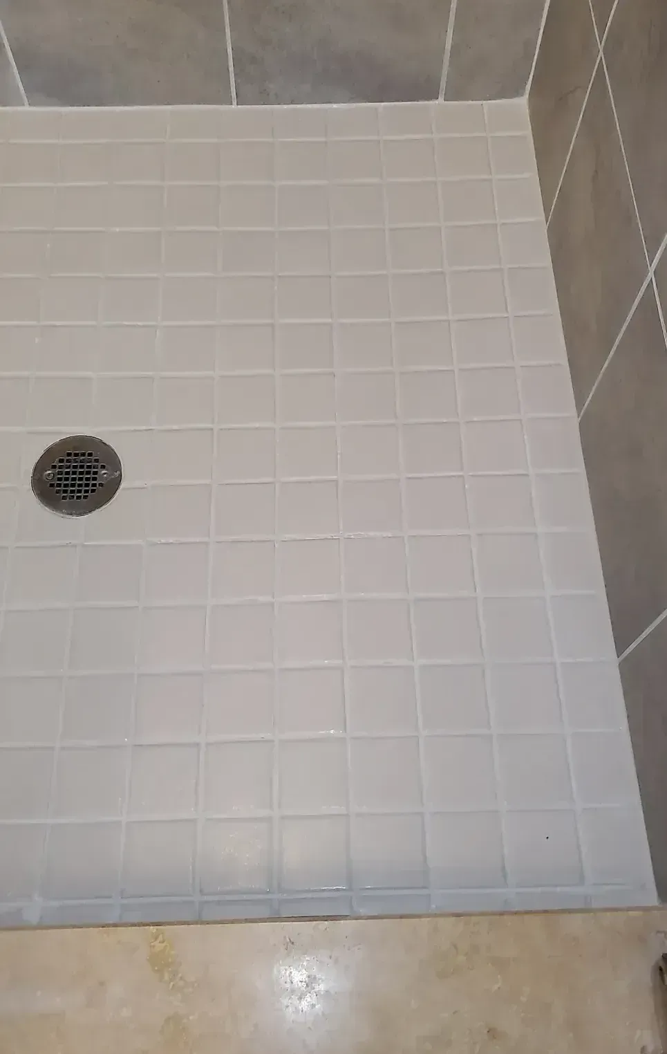 A white tiled floor in a bathroom next to a toilet.
