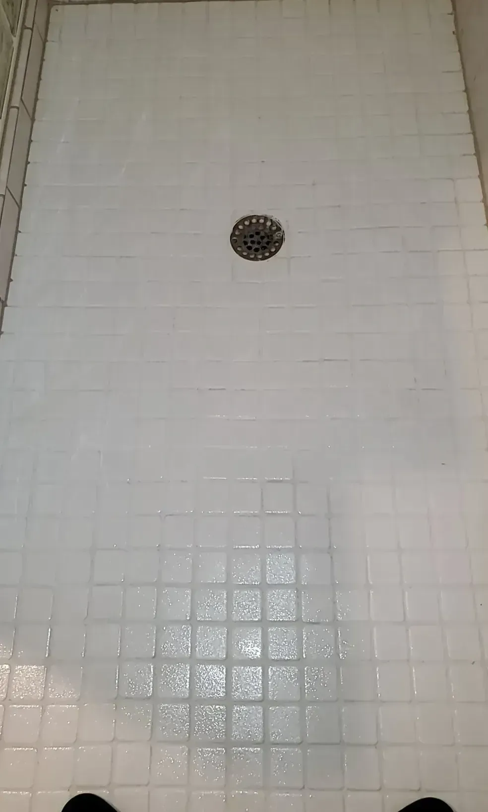 A bathtub in a bathroom with white tiles and chrome faucets.
