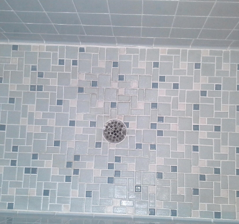 A shower floor with square tiles and a drain