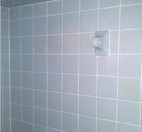 A shower with blue tiles and a white shower head