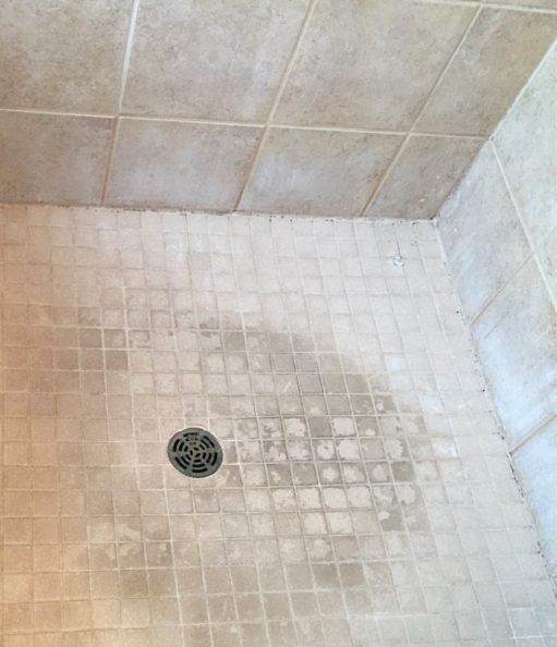 A shower stall with a drain in the middle of it.