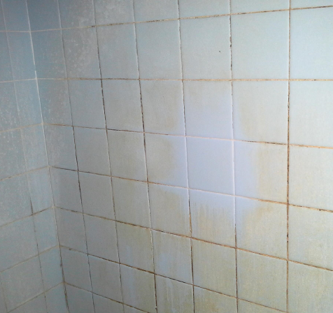 A white tiled wall with brown spots on it