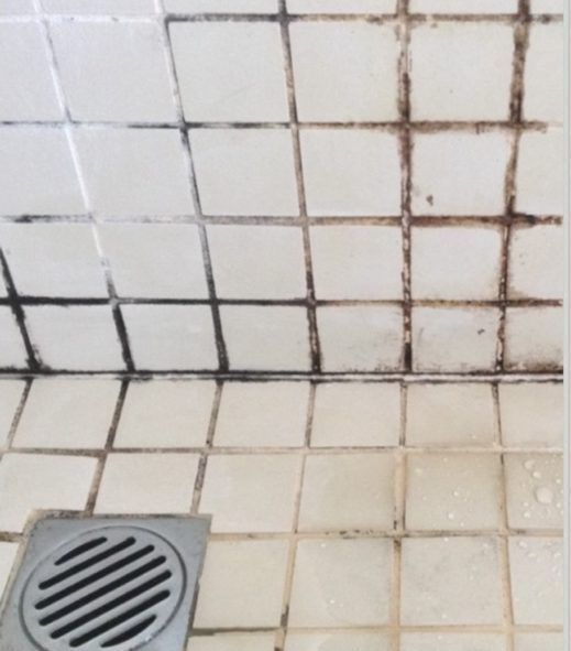 A drain in a bathroom next to a tiled floor