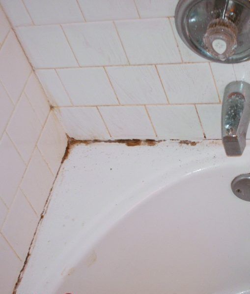 A bathtub in a bathroom with a tiled wall and a faucet.