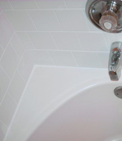 A white bathtub with a chrome faucet and a white tiled wall.