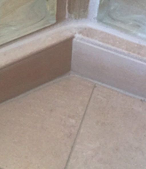 A close up of a tiled floor next to a shower door.