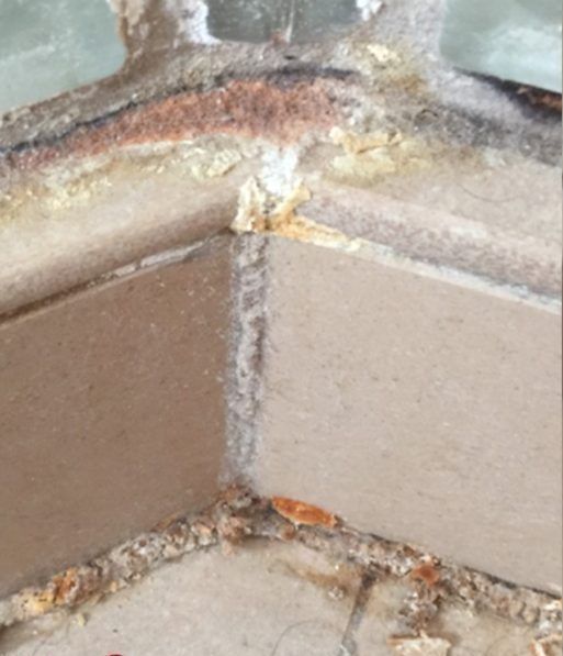 A close up of a corner of a tiled floor with a few pieces of wood on it.