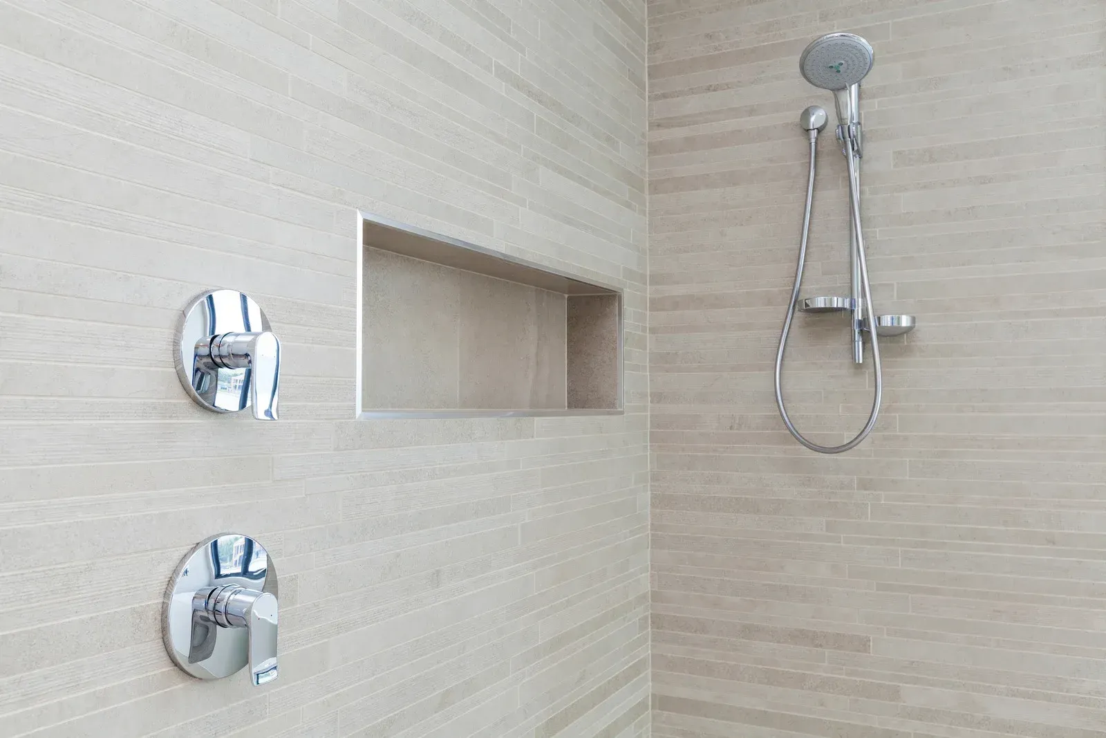 A bathroom with a shower and a shelf in the wall.